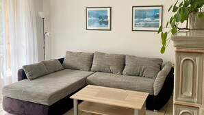 Moderni olohuone, jossa on kulmasohva, sohvapöytä ja kaksi kehystettyä kuvaa seinällä.