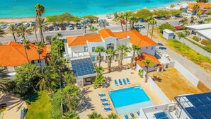 A resort with a swimming pool, beach access, and palm trees.