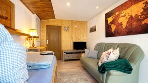 A cozy room with a bed, a sofa, a TV, and a world map on the wall. - Apartment 'Ferienwohnung Mit Aufenthaltsraum' with Shared Pool, Shared Terrace and Wi-Fi (Ruhland)