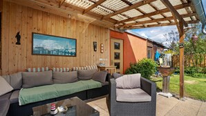 A covered patio with a sofa, a wicker chair, and a table. - Apartment 'Ferienwohnung Mit Aufenthaltsraum' with Shared Pool, Shared Terrace and Wi-Fi (Ruhland)