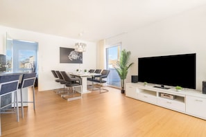 Un salon moderne comprenant un coin repas, un grand téléviseur à écran plat et une plante en pot.