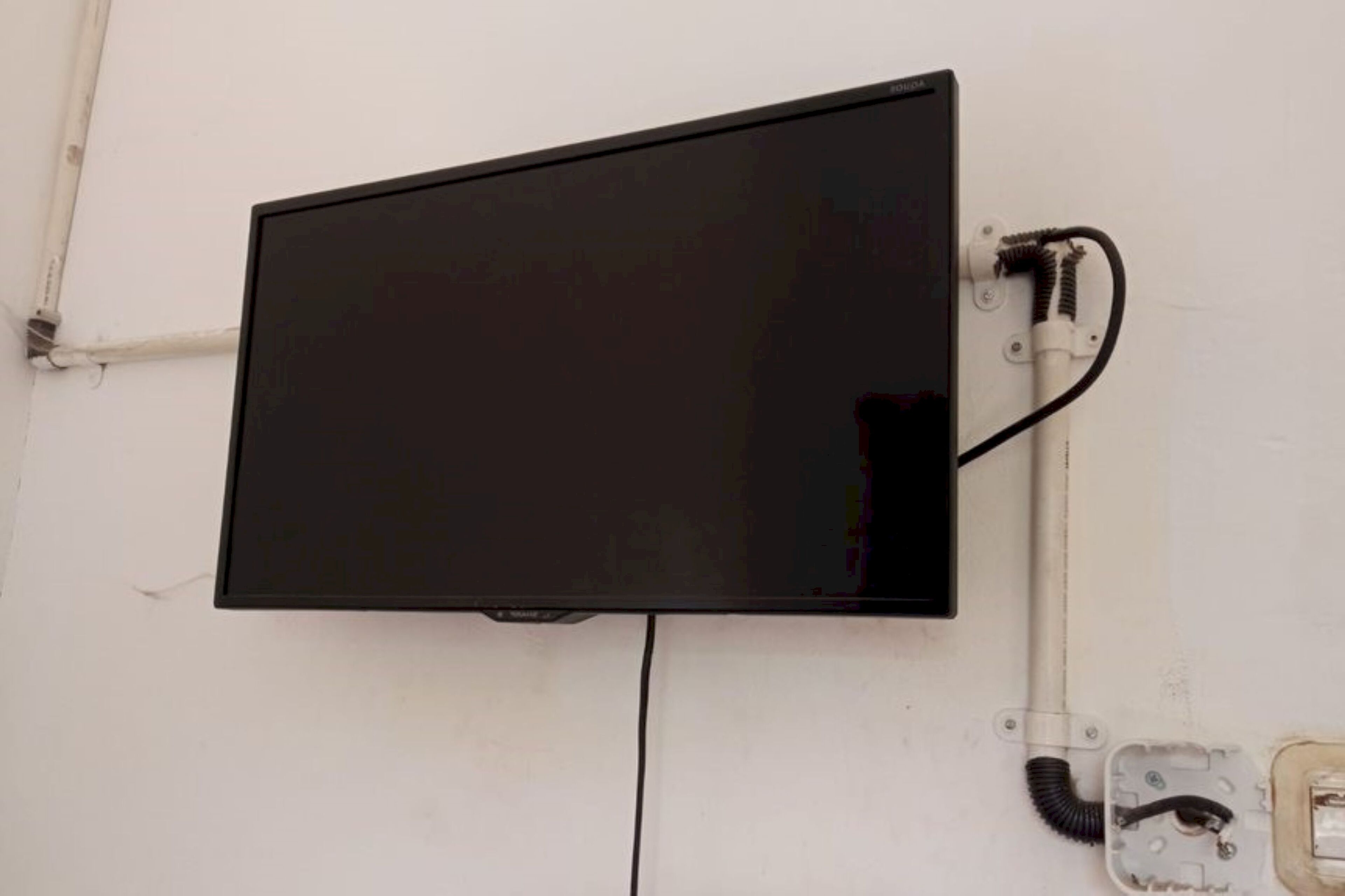 Et sort fladskærms-tv ophængt på en hvid væg.