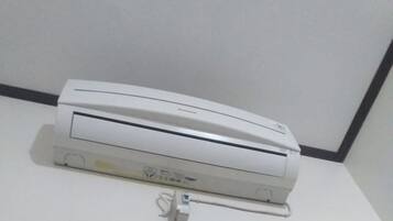 A white air conditioning unit mounted on a wall with a visible power cord.