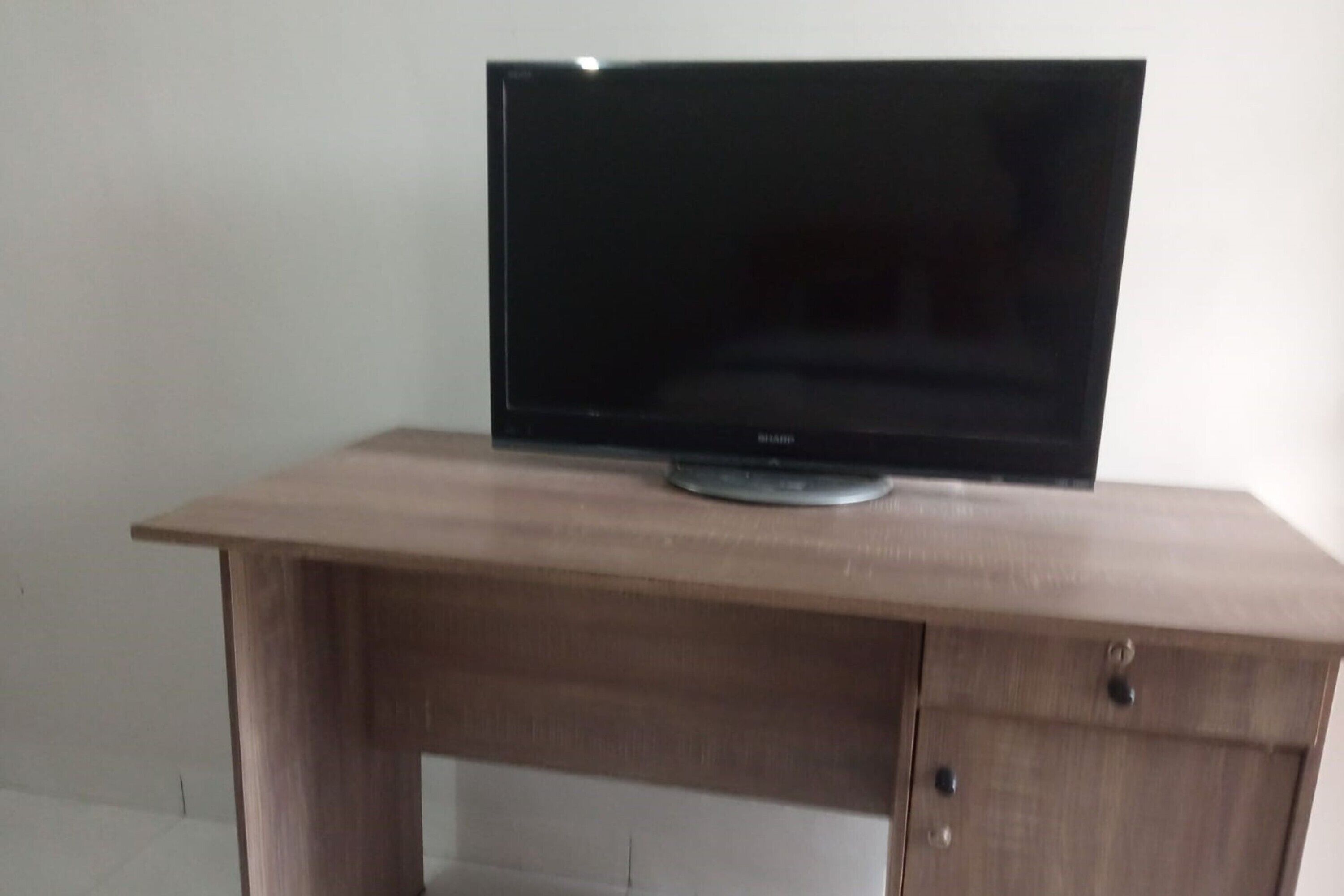 A wooden desk with a flat-screen TV on top.