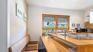 A modern kitchen with a wooden countertop, built-in sink, and a window with blinds.