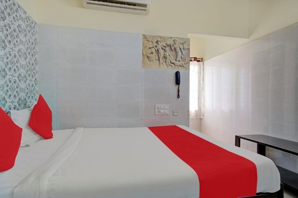 A hotel room with a bed, a telephone, and a wall-mounted artwork.