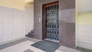 Een gebouwtravee met een metalen hekwerk en treden die naar een deur leiden.