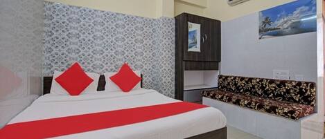 A hotel room with a bed, a sofa, an air conditioner, and a wall with a patterned design.