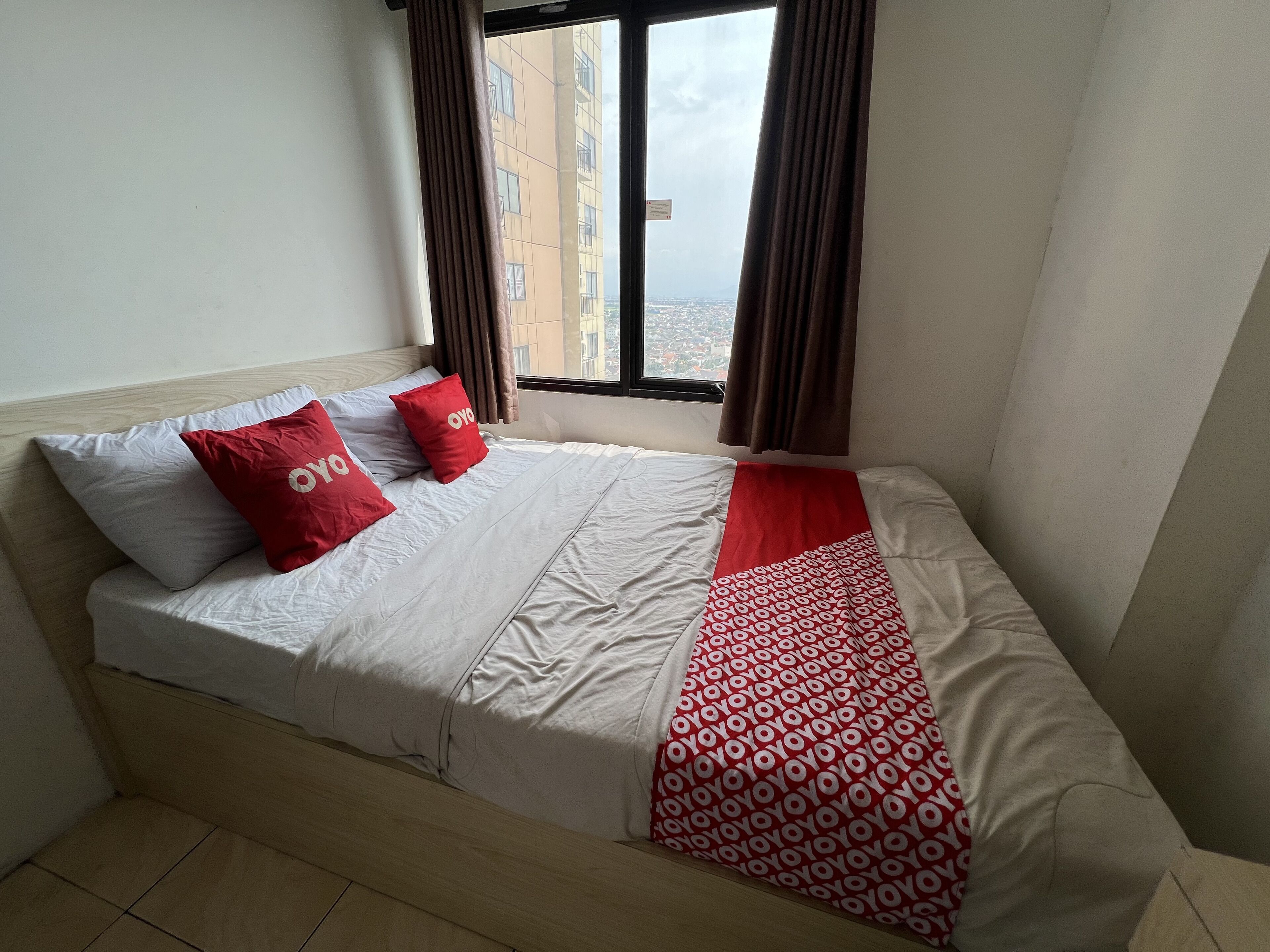A bed with white and red bedding, a patterned red blanket, and two red pillows with the word "oyo" on them.