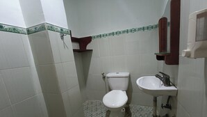 A small bathroom with a toilet, sink, and a mirror. - OYO 93828 Apartemen Tamansari Panoramic By Narel Room (Bandung)