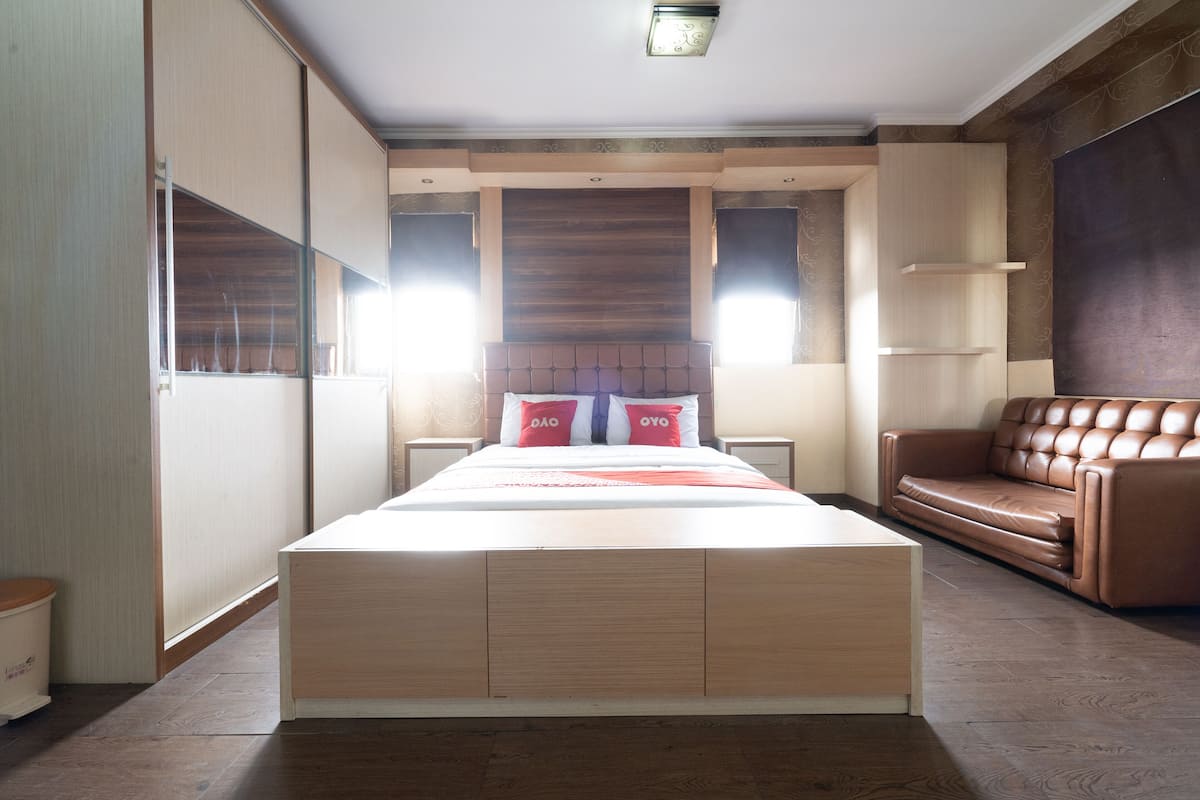 Un dormitorio con una cama grande, cabecera de madera y un sofá de cuero marrón.