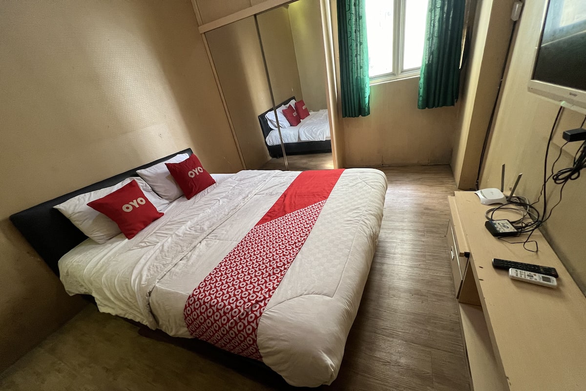 Habitación de hotel con cama, televisor y escritorio con control remoto.