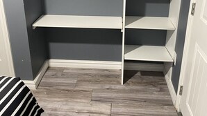 A room with a grey wall, a white door, and a white shelving unit with multiple shelves. - Cozy Get-Away Suite (Regina)