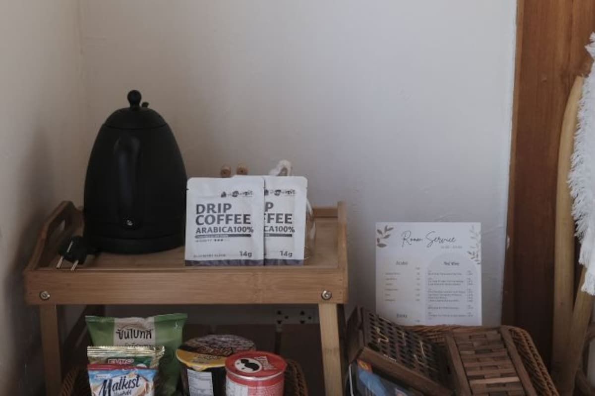 Una zona de cocina con un hervidor, sobres de café de filtro, un menú y una cesta de objetos.