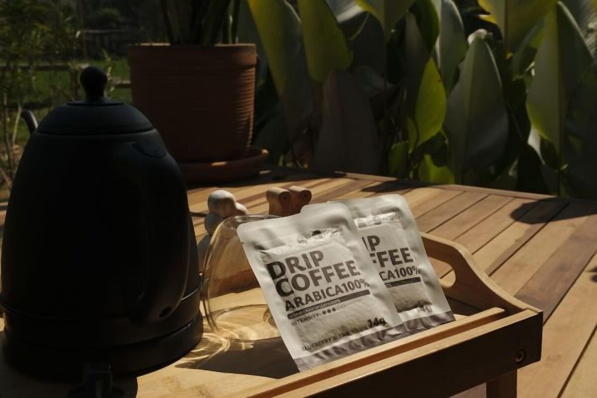 Una mesa de madera con un dispensador de café de filtro y dos sobres de café de filtro.