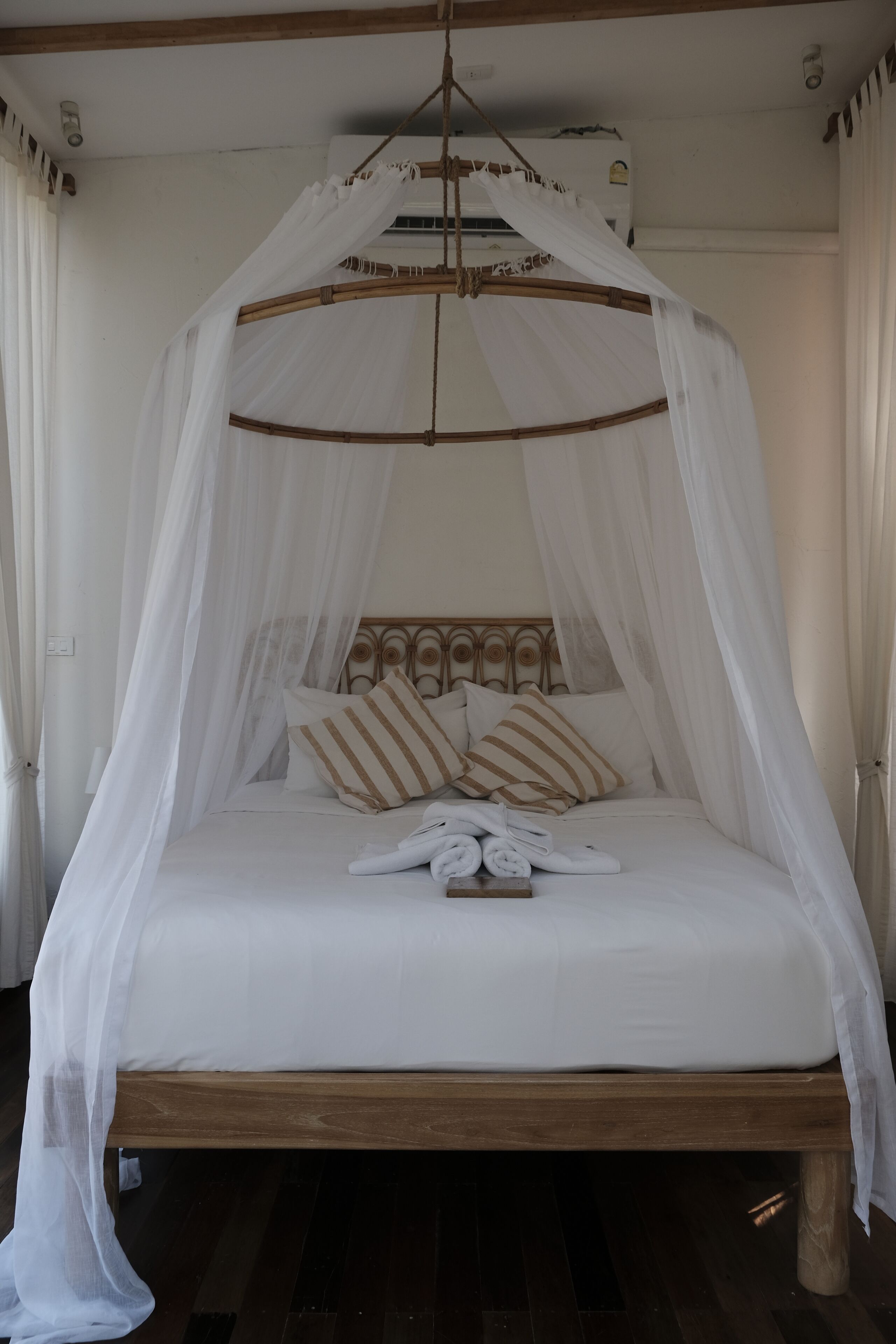 A bed with a canopy, pillows, and a folded towel.