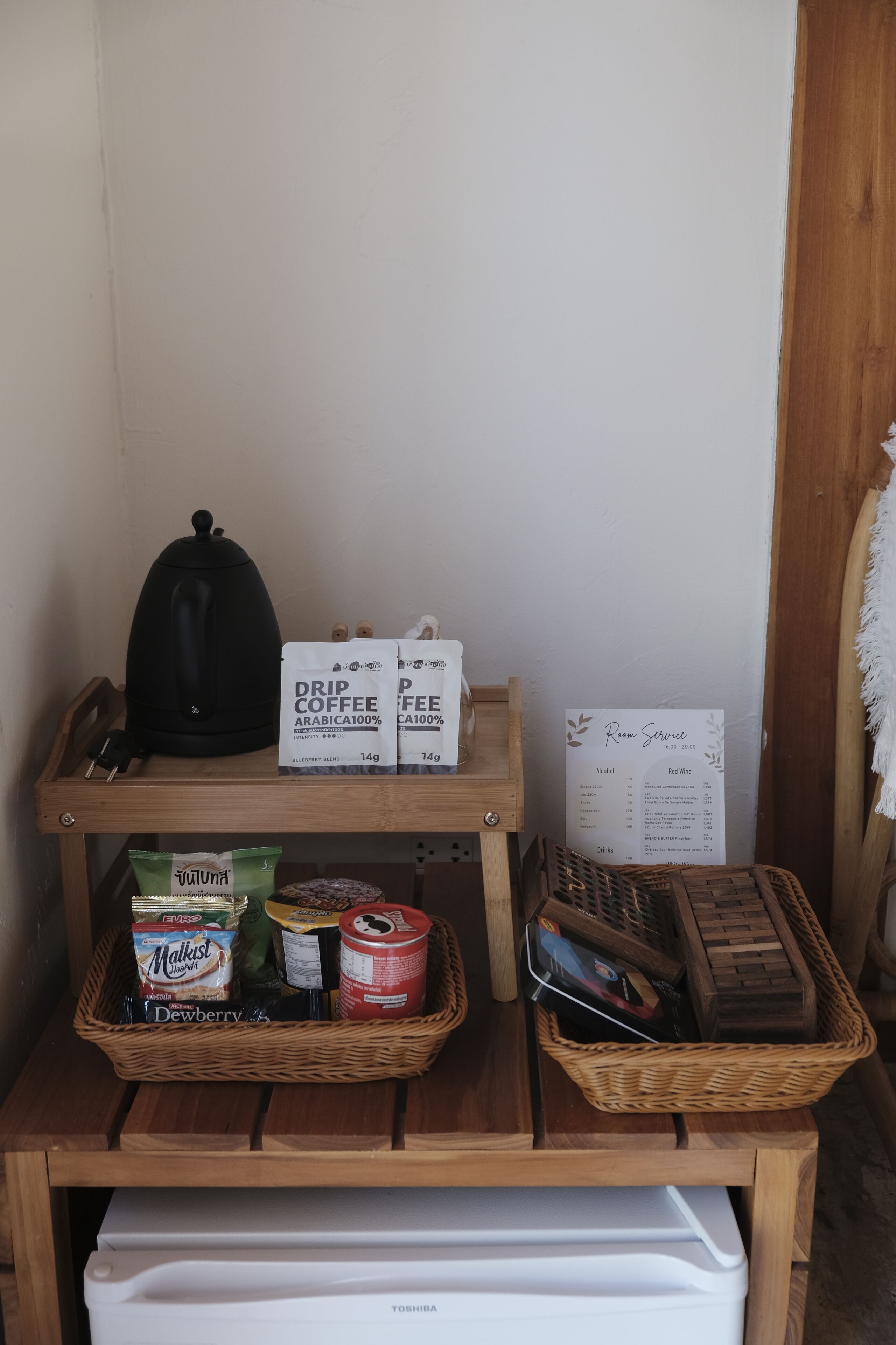 Una estación de café con sobres de café de filtro, una tetera y un menú.