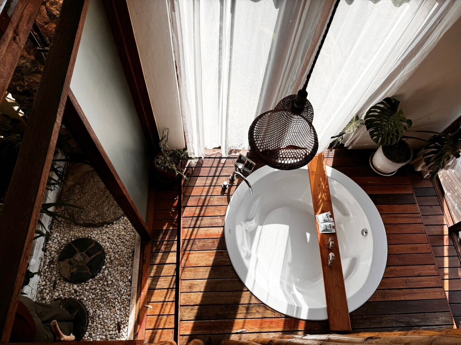 A wooden deck with a white sink, a hanging net, and potted plants.