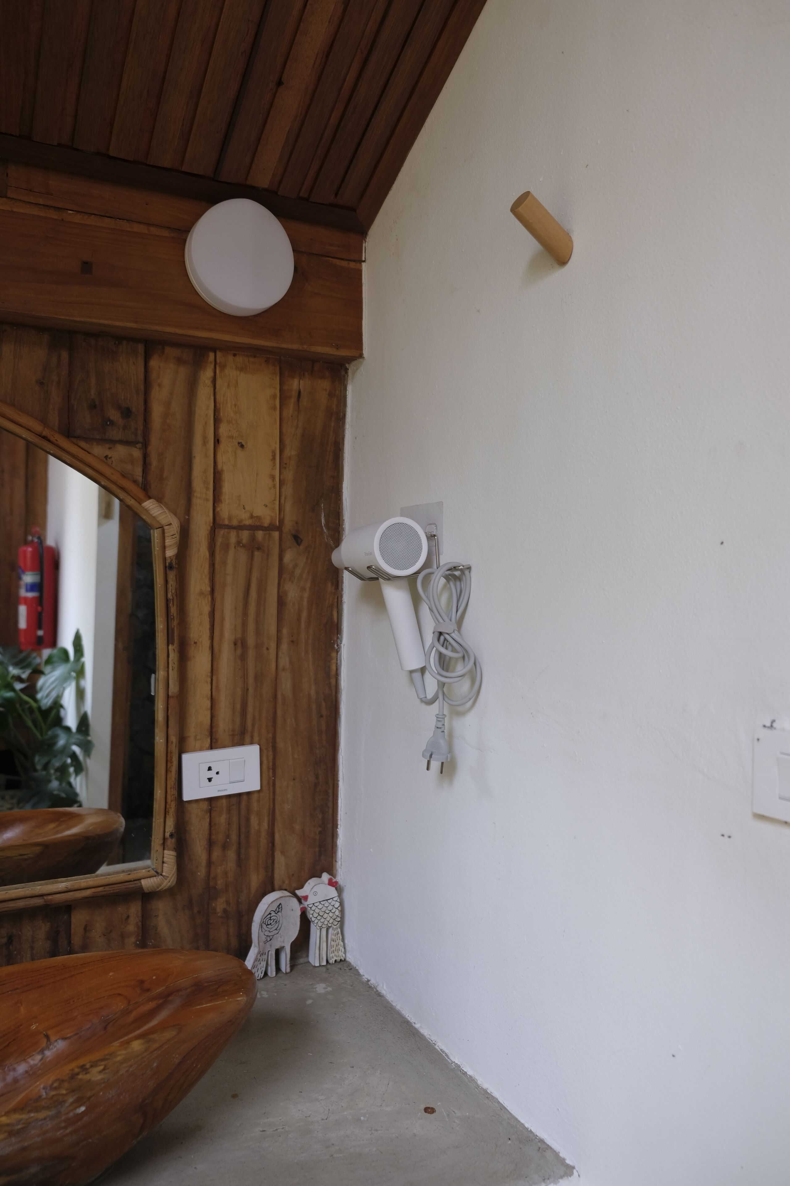 Une salle de bain avec des murs en bois, un plafond blanc, un miroir, un sèche-cheveux et une prise de courant.