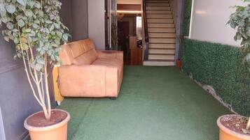 Una habitación con un sofá, una escalera y plantas en macetas.