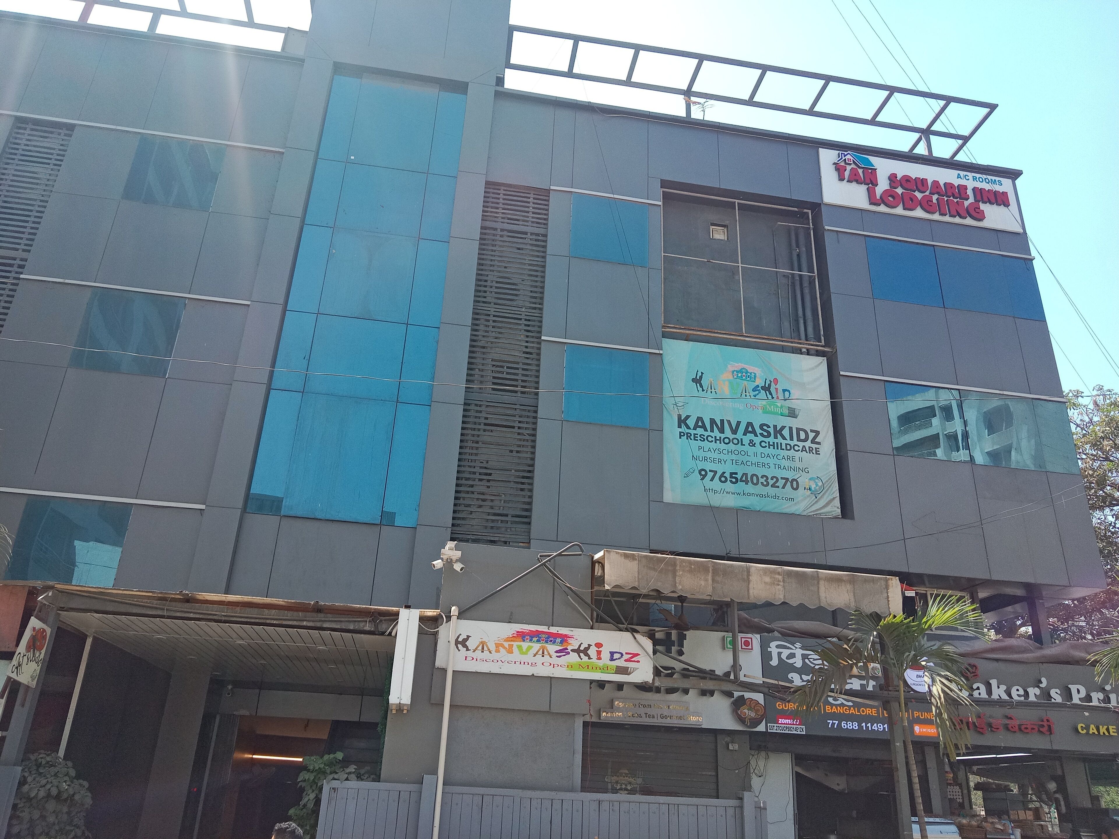 Un edificio de varios pisos con señalización que indica 'AIC Rooms' y 'Kanjvaskidz Preschool & Childcare'.
