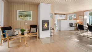 Un intérieur moderne avec des murs lambrissés, une cheminée, un coin repas et une cuisine.