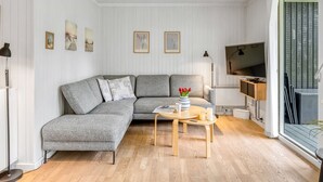 Un salon moderne avec un canapé d’angle gris, une table basse en bois et un téléviseur à écran plat.