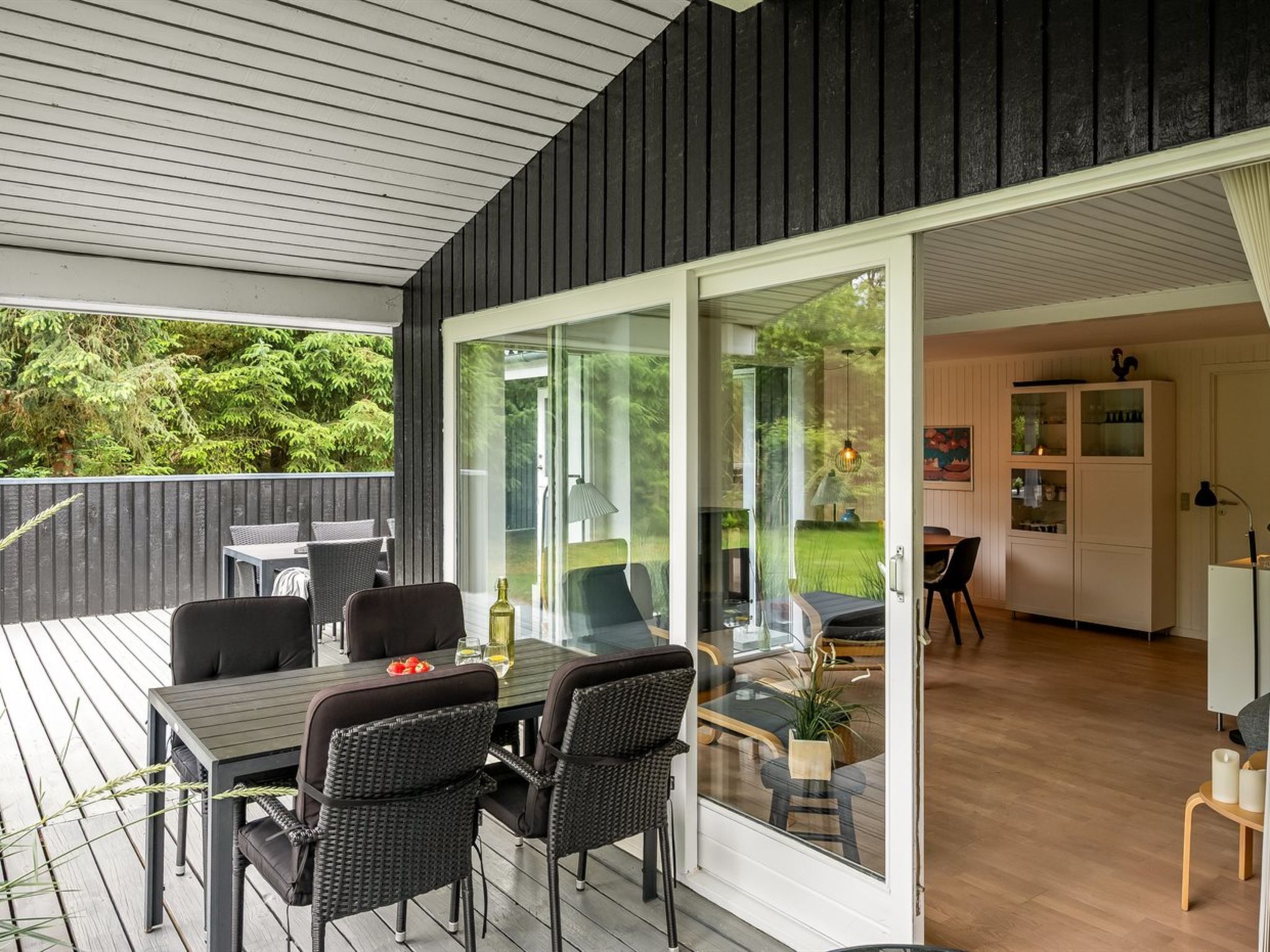 Een moderne eethoek buiten, met een glazen deur naar een keuken en een terras.