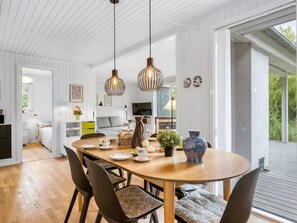 A modern dining area with a wooden table, upholstered chairs, pendant lighting, and a view of the outdoors. - "Atla" - 2.5km from the sea by Interhome (Blåvand)