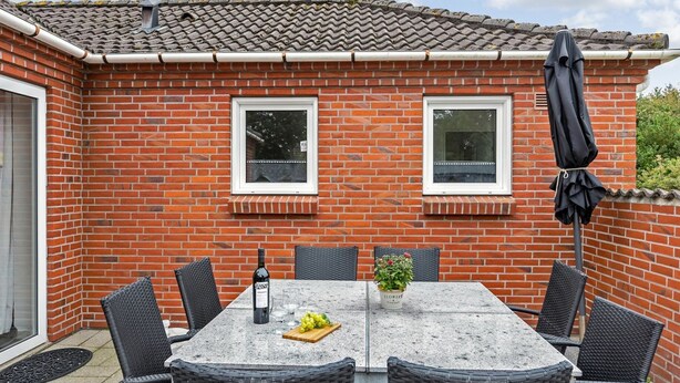 Eine Terrasse mit Tisch, Stühlen, einer Weinflasche und einem Blumentopf.