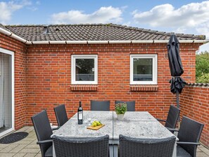 A patio with a table and chairs, a bottle of wine, and a potted plant. - "Pernilla" - 2km from the sea by Interhome (Blåvand)