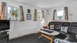 Ein modernes Wohnzimmer mit einem schwarzen Ledersofa, einem kleinen Couchtisch und einem Flachbildfernseher.