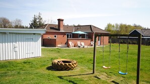 Ein Garten mit Schaukeln, einer Reifen-Schaukel und einem Geräteschuppen.