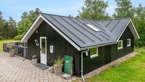 Een gebouw van zwart metaal met een schuin dak, een deur en ramen.