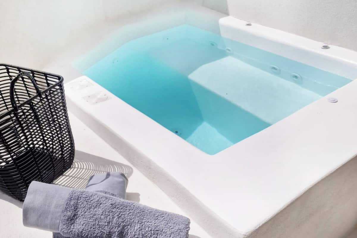 A spa area with a hot tub, a towel, and a black basket.