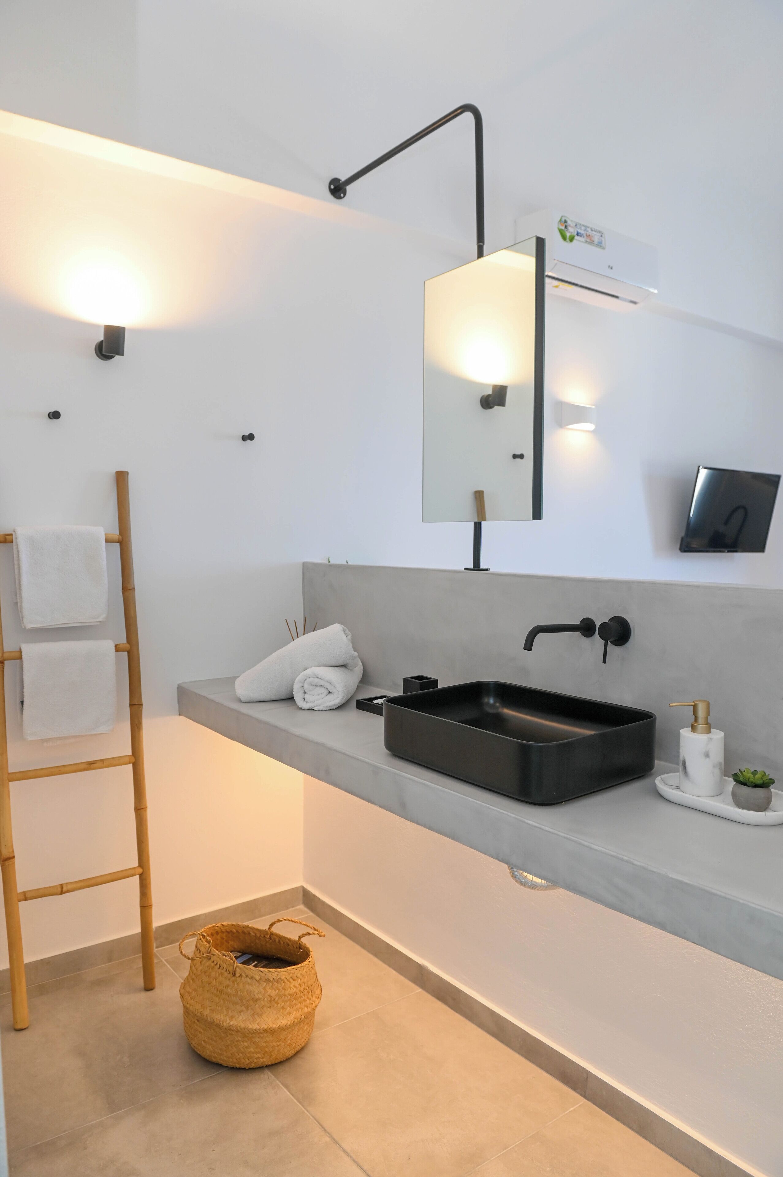 A modern bathroom with a rectangular black sink, a mirror, and a wall-mounted light fixture.