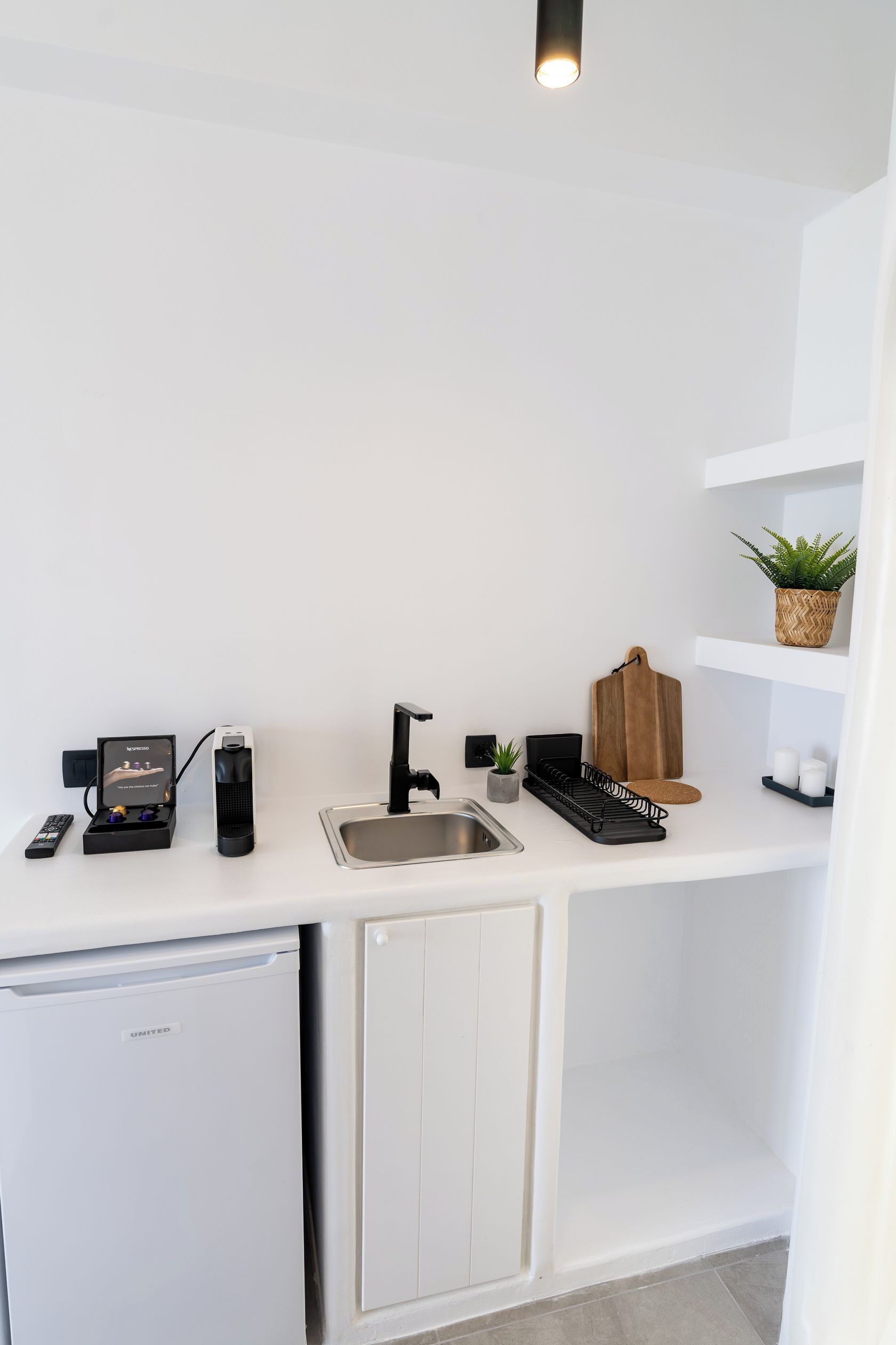 A compact kitchen with a refrigerator, sink, and a coffee machine.