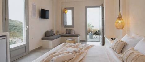 Ein Schlafzimmer mit einem großen Bett, einer Sitzecke, einem Fernseher und einem Balkon.