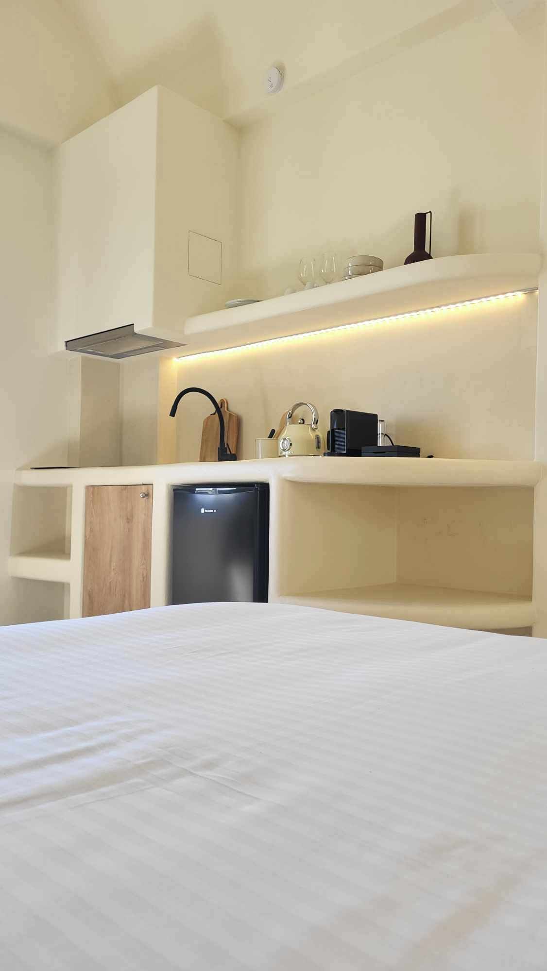 Een knus hotelkamer met een bed, een kitchenette en een kleine koelkast.