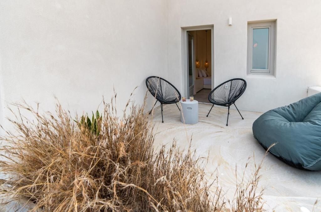 A small outdoor seating area with two black wire chairs and a blue bean bag.