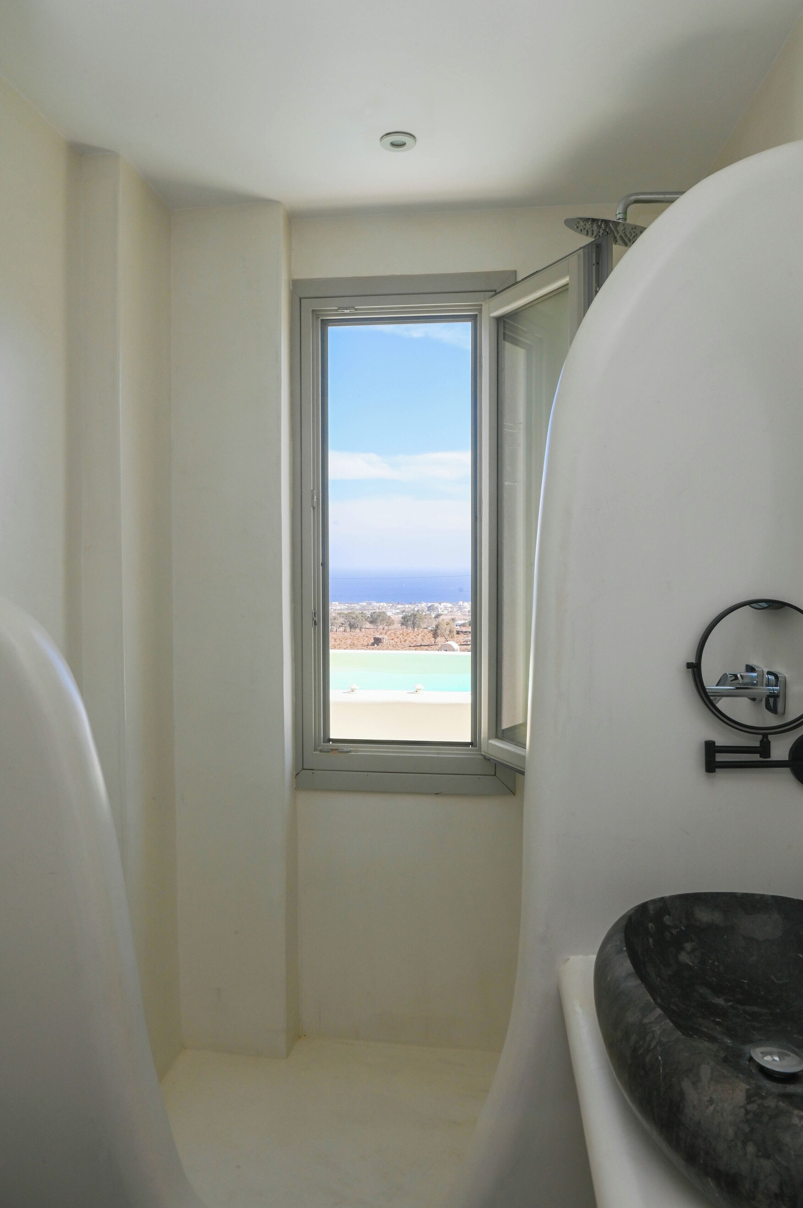 A bathroom with a view of a beach and ocean through a window.