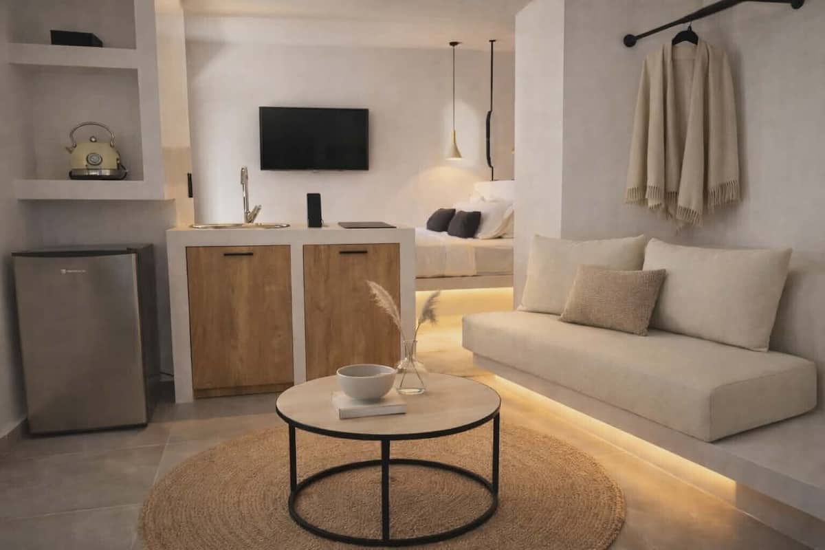 A modern living room with a sofa, a coffee table, a TV, and a kitchen area.