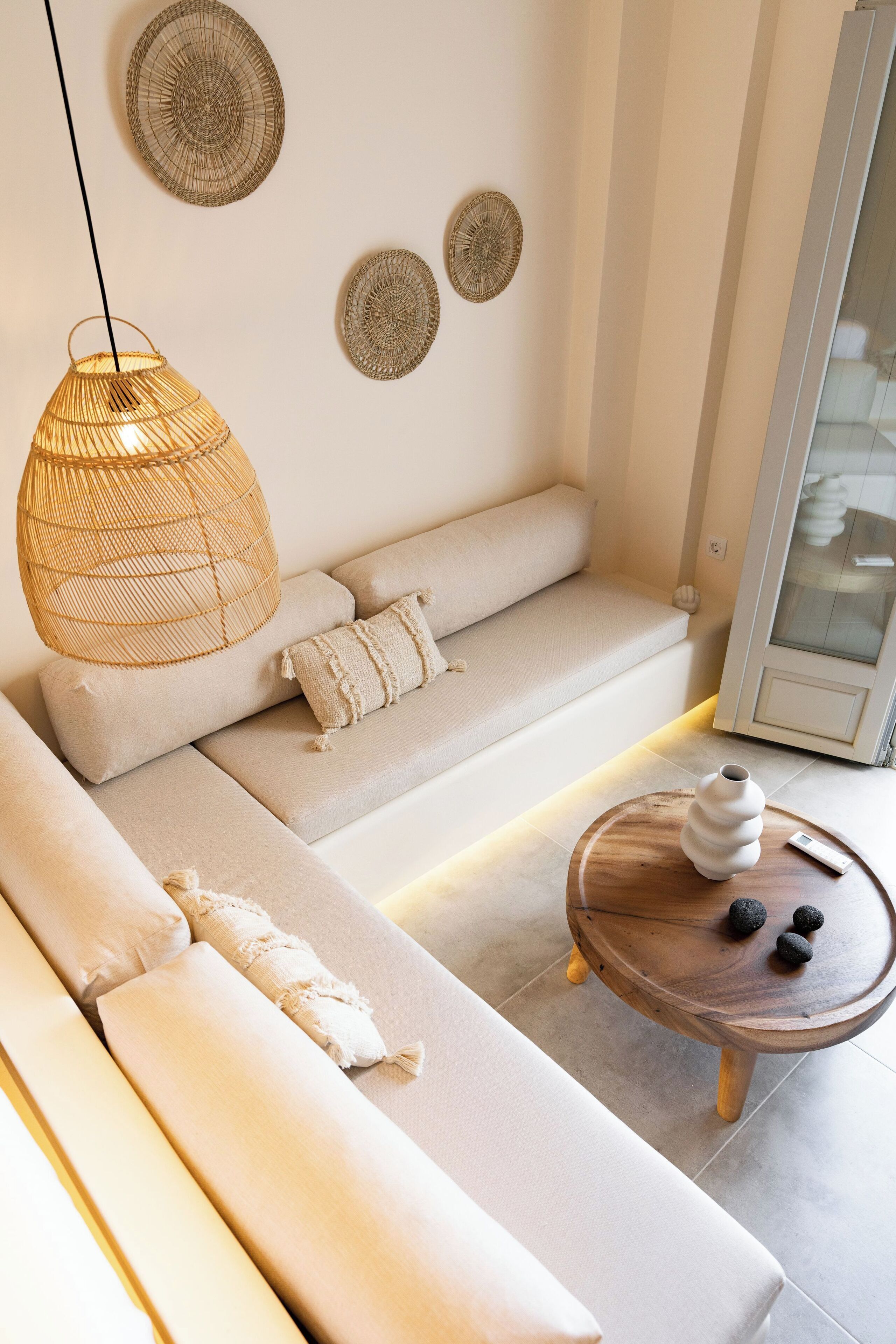 A modern living room with a sofa, a hanging light fixture, and a wooden coffee table.