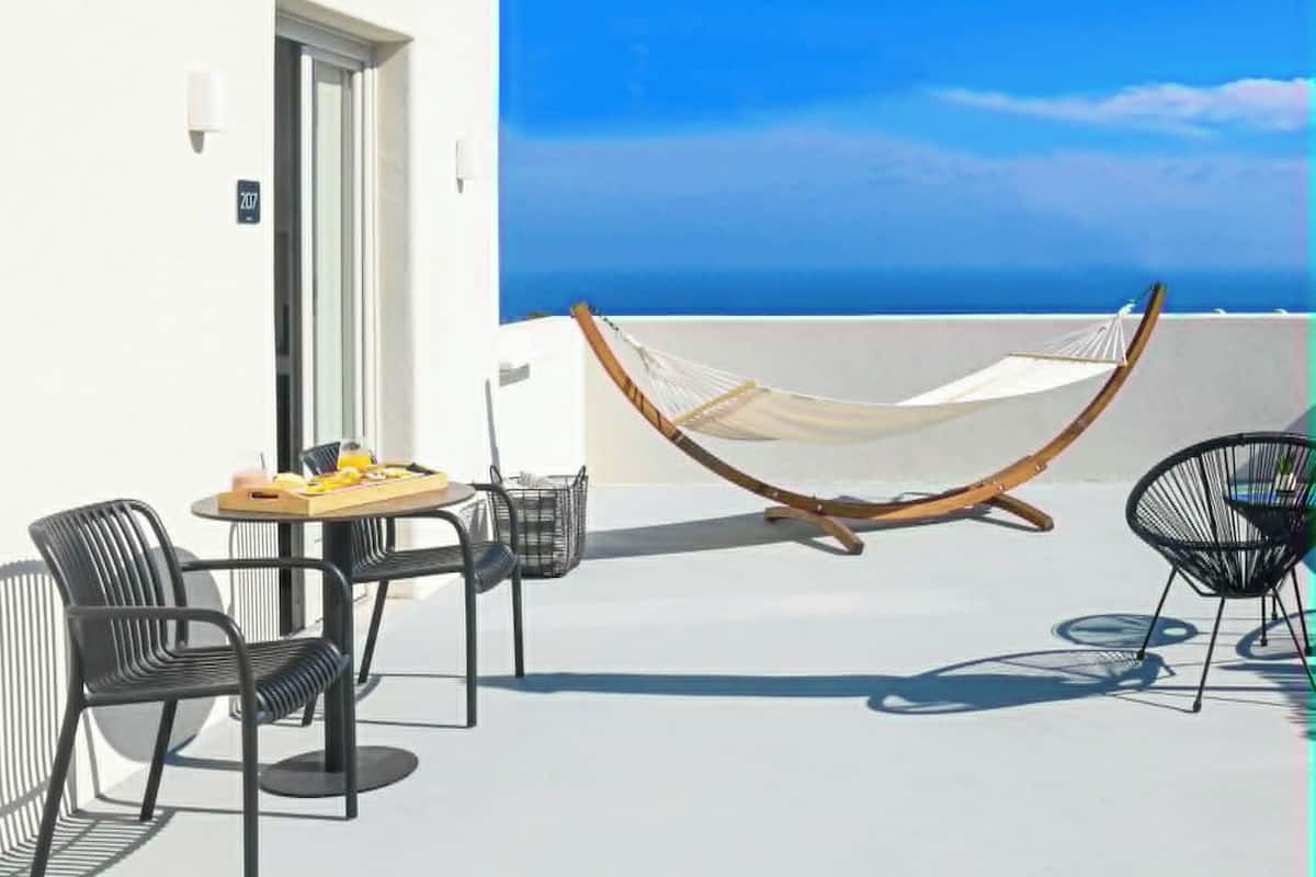 A balcony with a hammock, a table with a tray of fruit, and two chairs.