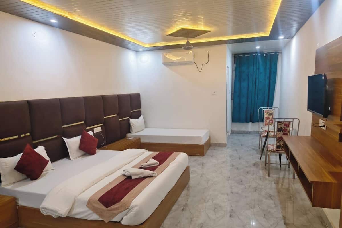 Quarto de hotel com duas camas, televisão, escrivaninha e uma cadeira.