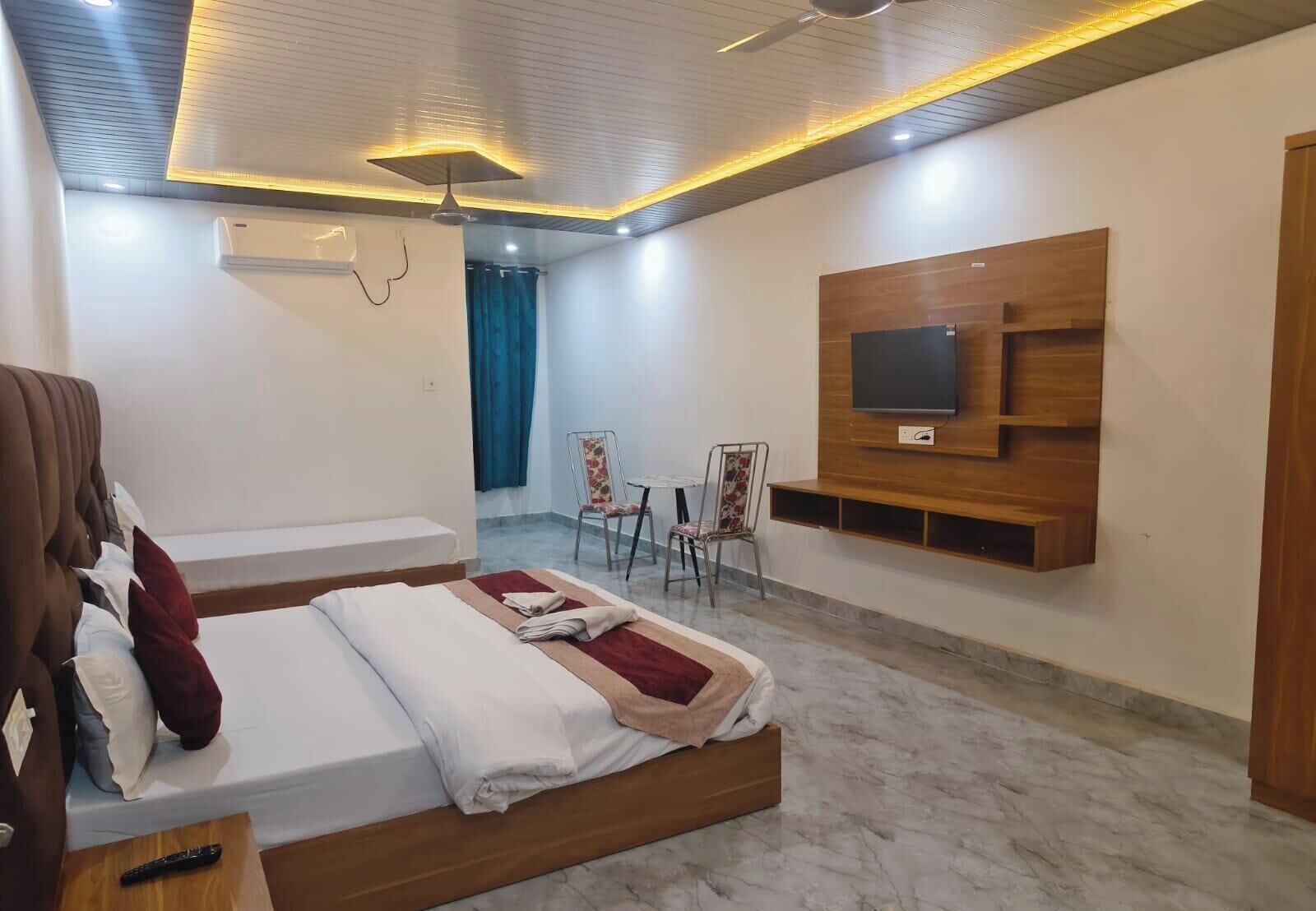 Una habitación de hotel con una cama, un televisor montado en la pared, una silla y una mesita.