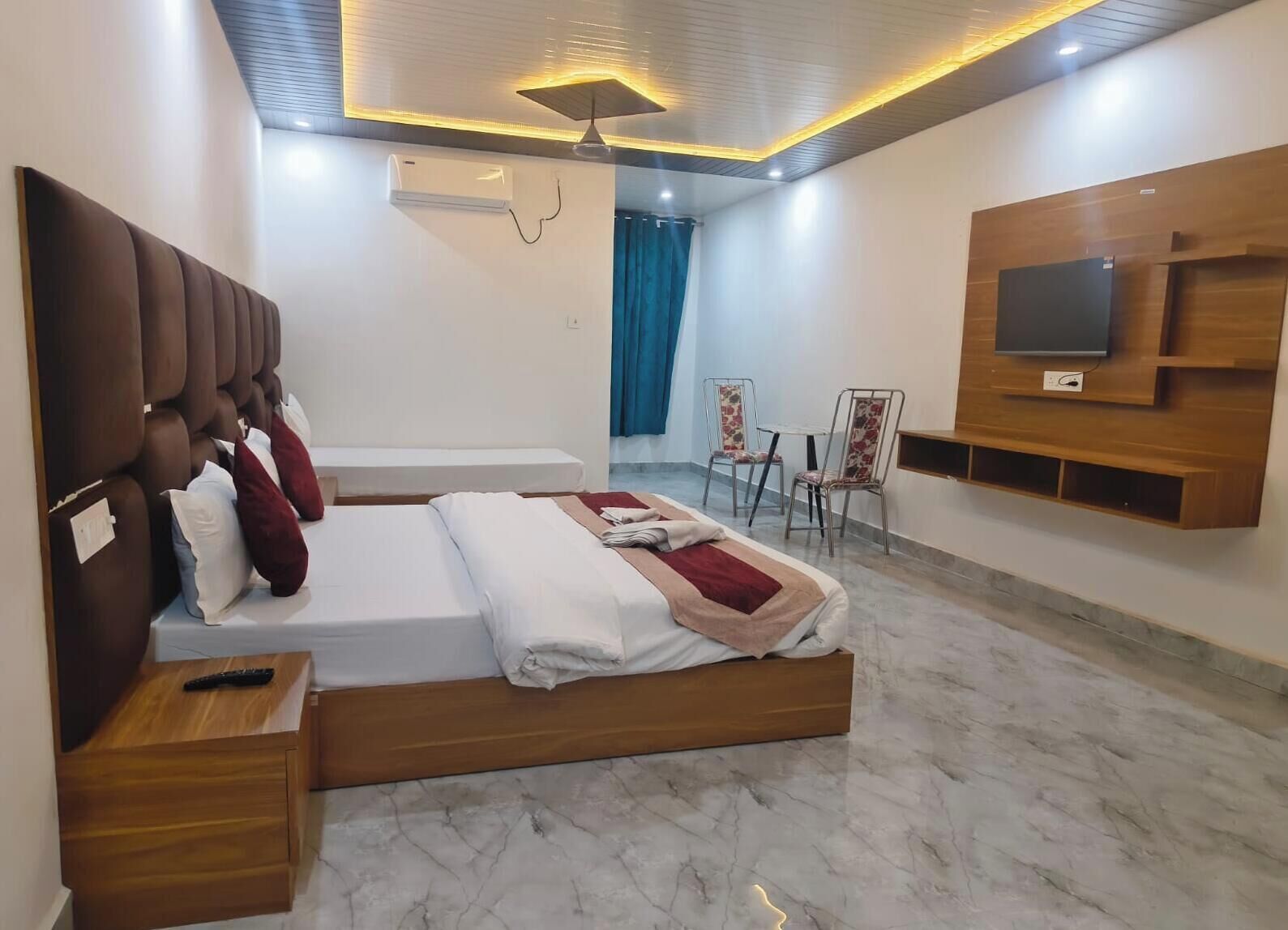 Una camera d'albergo moderna con un letto grande, una TV fissata al muro, un tavolino e una sedia.