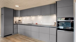 A modern kitchen with grey cabinets, a wooden floor, and built-in appliances including an oven and a coffee maker. - "Dirtje" - 200m from the sea by Interhome (Blåvand)