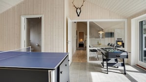 Un intérieur moderne agrémenté d’une table de ping-pong, d’un baby-foot et d’un grand miroir qui reflète l’espace repas.