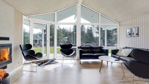 Un salon moderne avec une cheminée, des canapés en cuir noir et un plafond en verre.
